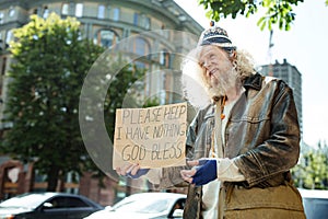 Long-haired homeless man standing near traffic asking for help