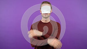 Long haired man isolated on purple background wearing protective medical mask over eyes