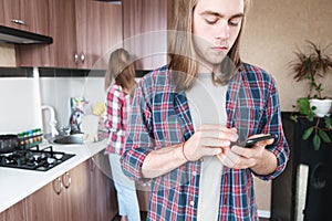 A long-haired man with a phone in his hands dials SMS or calls the food and medicine. delivery service home while