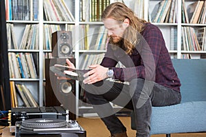 Long haired man putting a vinyl on the turntable