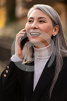 Long-haired mid aged woman with a smartphone looking anticipated