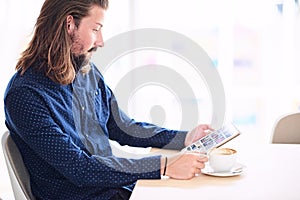 Long haired modern man with tablet sitting next to window photo