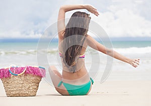 long haired woman in bikini and with straw bag lying on tropical beach. Maldives