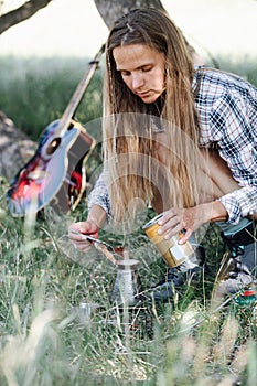 Long-haired woman crouching in a shadow, adding coffee powder in a cezve