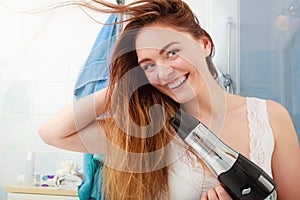 Long haired woman drying hair in bathroom