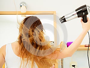 Long haired woman drying hair in bathroom rear view