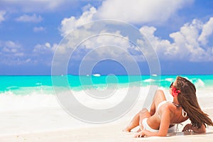 Long haired woman with flower in hair in bikini at tropical beach