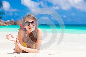 Long haired woman with flower in hair in bikini on tropical beach