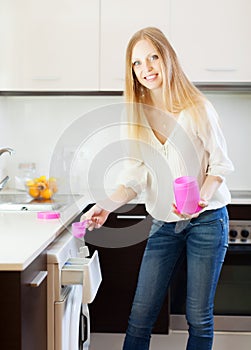 Long-haired woman putting whitener in to washing machine