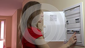Long-haired woman turning on light-switch at power control panel at home