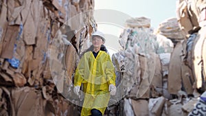 Long-haired woman walks past pile of trash at waste factory