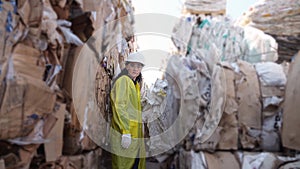 Long-haired woman walks past pile of trash at waste factory