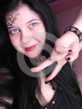 Long-haired young Caucasian gothic girl with black hair, in black clothes, with a cross on her neck