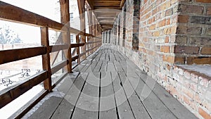 Long hallway in ancient castle. Wooden boards and bricks.