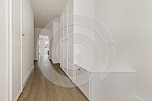 Long hallway of a house with built-in wardrobes with white wooden doors and access to several rooms