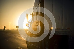 Long Haul 18 Wheel Truck driving on a highway at sunrise or sunset