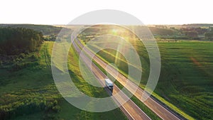 Long Haul Semi Truck Driving On Highway In Rural Hilly Region At Sunset