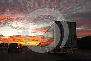 Long haul truck driving on a desert highway at sunrise or sunset
