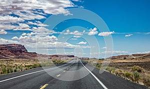 Long highway in the american desert, blue cloudy sky background