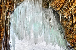 Long icicles on arch of small grotto in coastal rock