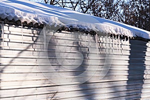 Long icicles hang from roof house.On a sunny spring day.