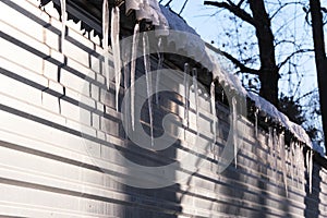 Long icicles hang from roof house.On a sunny spring day.