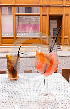 Long Island cocktail and Spritz Aperol with straws on table. Mixed alcoholic cocktails on table. Drinks in outdoor bar.