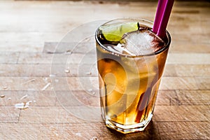 Long island iced tea cocktail with lime, ice and served with pink straw