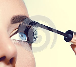 Long lashes closeup. Beautiful woman applying mascara on her eyes