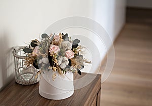 Long lasting flowers decoration. Preserved roses with dried flowers bouquet closeup. Selective focus on home decoration made of