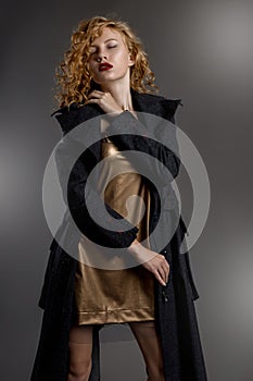 long-legged girl with gorgeous hair and beautiful eyes in a seductive short golden dress and gray coat in Gothic style