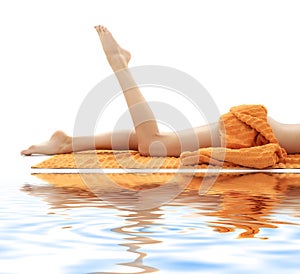 Long legs of girl with orange towel on white sand