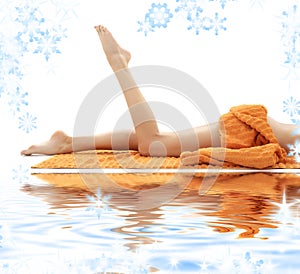 Long legs of girl with orange towel on white sand