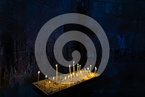 Long lighted candles group on black background