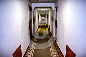 Long lighted corridor with many doors and carpeted floor