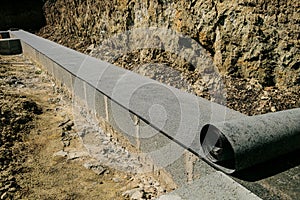 Long line of rolled bitumen waterproofing material in two layers lies on the masonry of concrete blocks photo