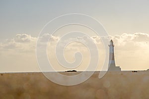 Long, low angle shot of lighthouse beyond bokeh effect sand