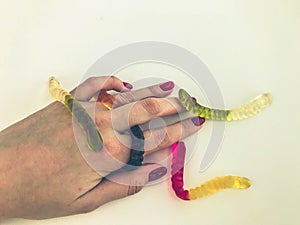 Long, mouth-watering, multi-colored worms lie on the girl`s hand with a bright red manicure. edible worms crawl in the palm of