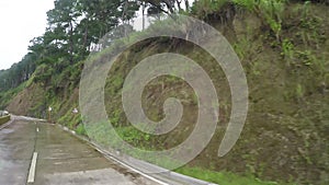 Long narrow concrete paved winding zigzag road at the side of mountainous Cordillera cliffs on misty and day.