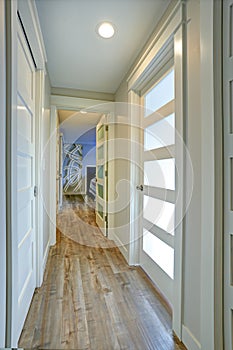 Long, narrow corridor with white doors accented with glass panels