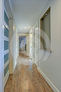 Long, narrow corridor with white doors accented with glass panels