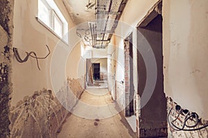 Long and narrow corridor with windows, doors, cable trays and walls with not installed electrical cables in an apartmen