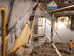 Long narrow yellow bridge with metal railing under the big concrete road bridge