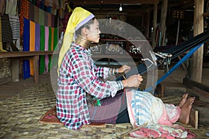 Long-necked Kayan Lahwi woman weave on traditional device