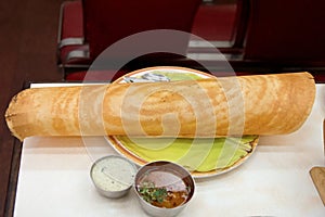 A Long paper thin Dosa served with coconut chutney and aromatic sambar.