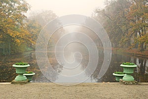 Long park pond in foggy autumn morning