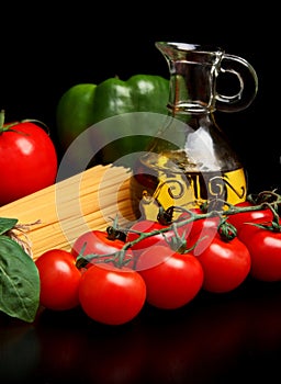 Long pasta raw on black with tomatoes and olive oil