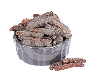 Long pepper in black bowl, isolated on white background. Heap of pippali or piper longum. photo