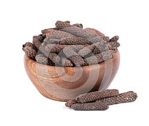 Long pepper in wooden bowl, isolated on white background. Heap of pippali or piper longum.