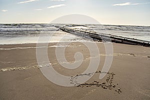 Long pier boardwalk leading out onto a Baltic sea, sunrise long way out with heart drawn in sand